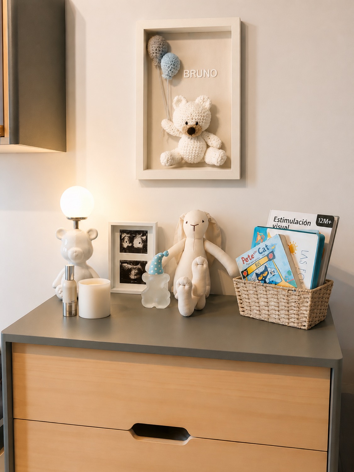 Cómoda del cuarto del bebé con juguetes, libros y un cuadro apoyado