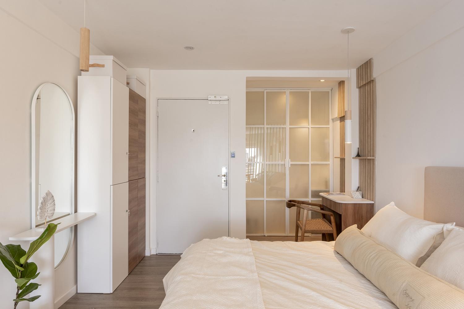 Vista del dormitorio del monoambiente India hacia el baño, con el espejo arco y la carpintería de madera