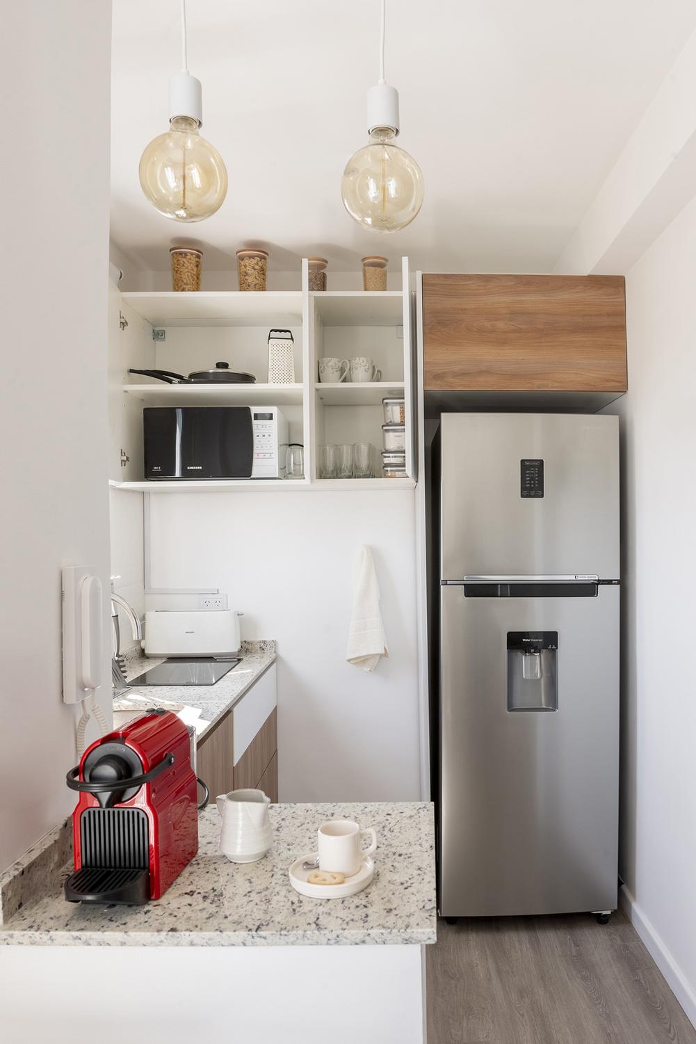 Detalle del desayunador y la mesada de granito de la cocina, con cafetera y colgantes de vidrio
