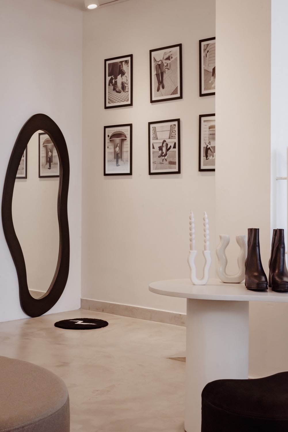Sala blanca de Rakhi con espejo de contorno irregular y una serie de fotografías enmarcadas