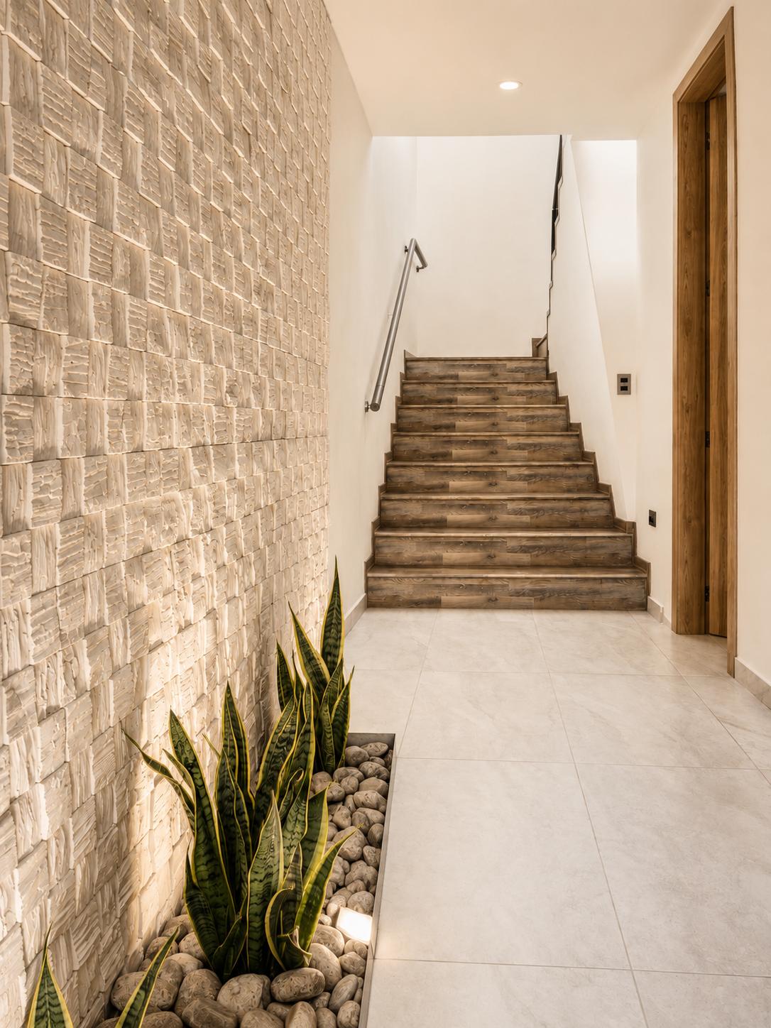 Escalera de la casa Sevillana junto a un muro de piedra iluminado desde abajo
