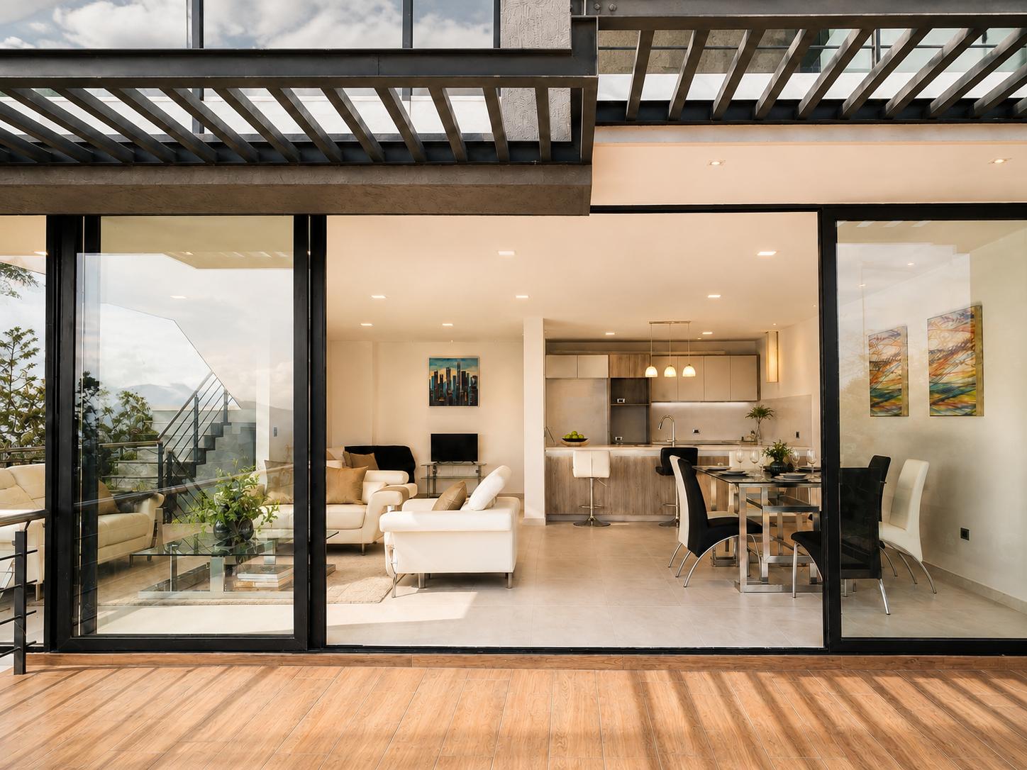 Galería exterior de la casa Sevillana con pérgola y el comedor visto a través del ventanal